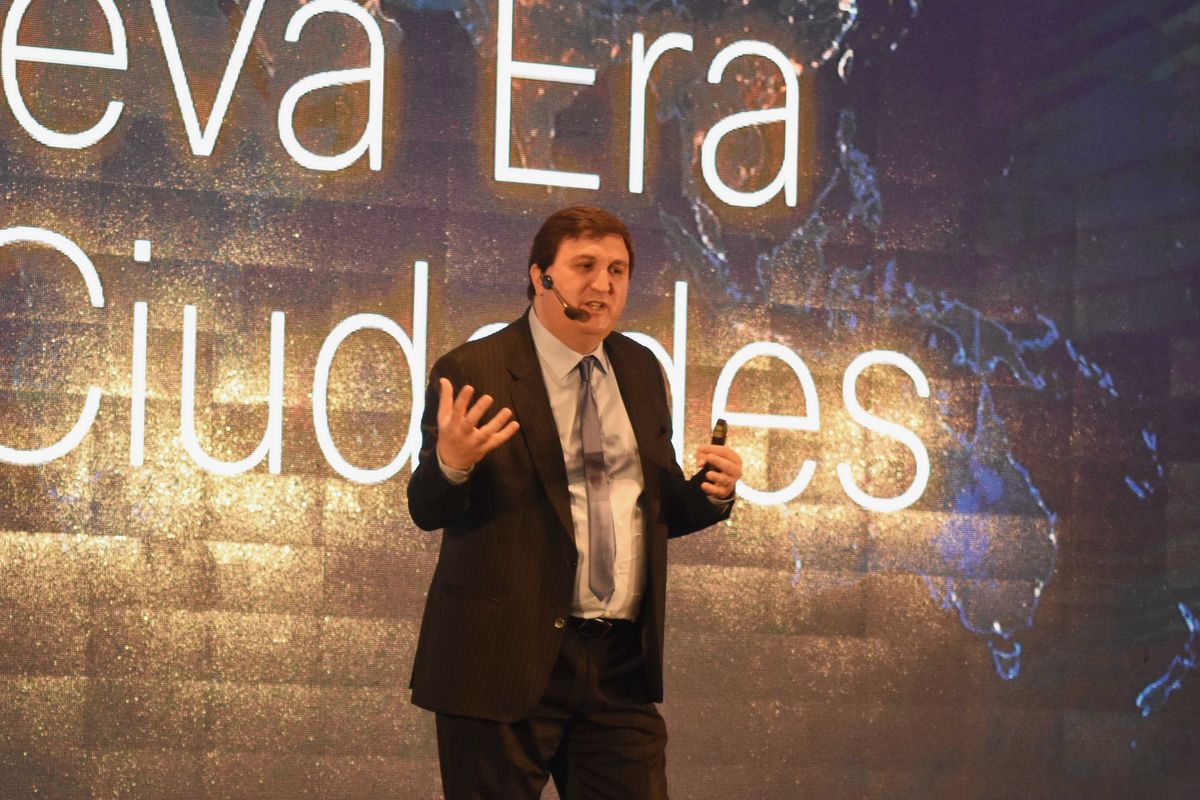 Mariano en el escenario bajo una slide sobre una nueva era para las ciudades